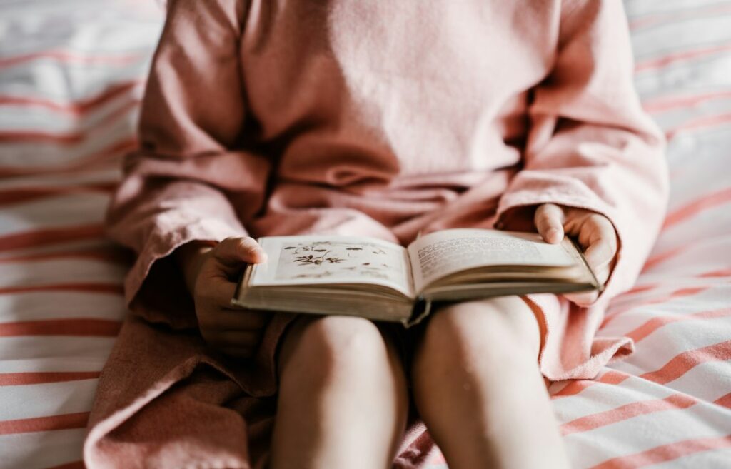 A girl reading a bedtime story in a softly lit room, representing meaningful stories at the end of the day