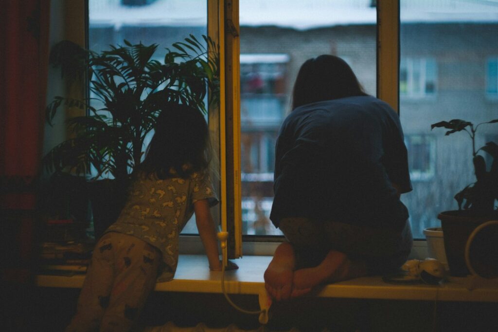 A parent and child sharing a quiet moment by a window, representing honesty, trust and difficult conversations