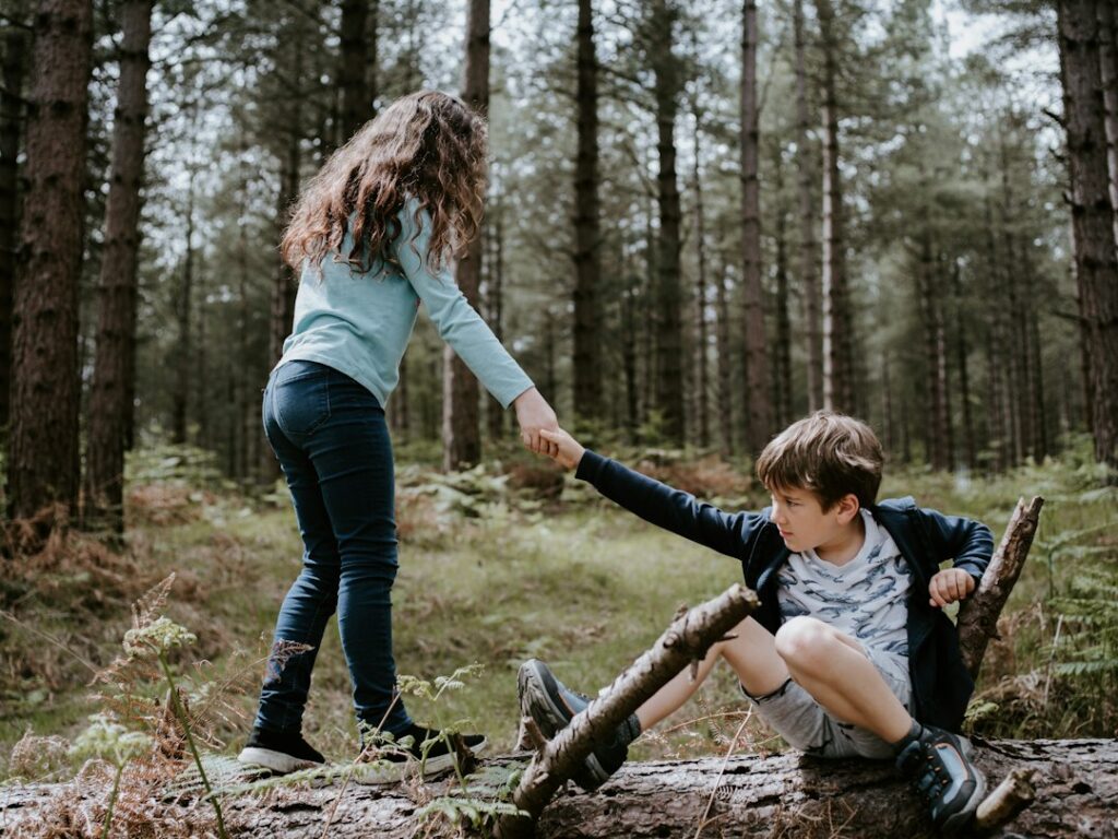 Two children helping each other outdoors, representing kindness, empathy and supportive friendship