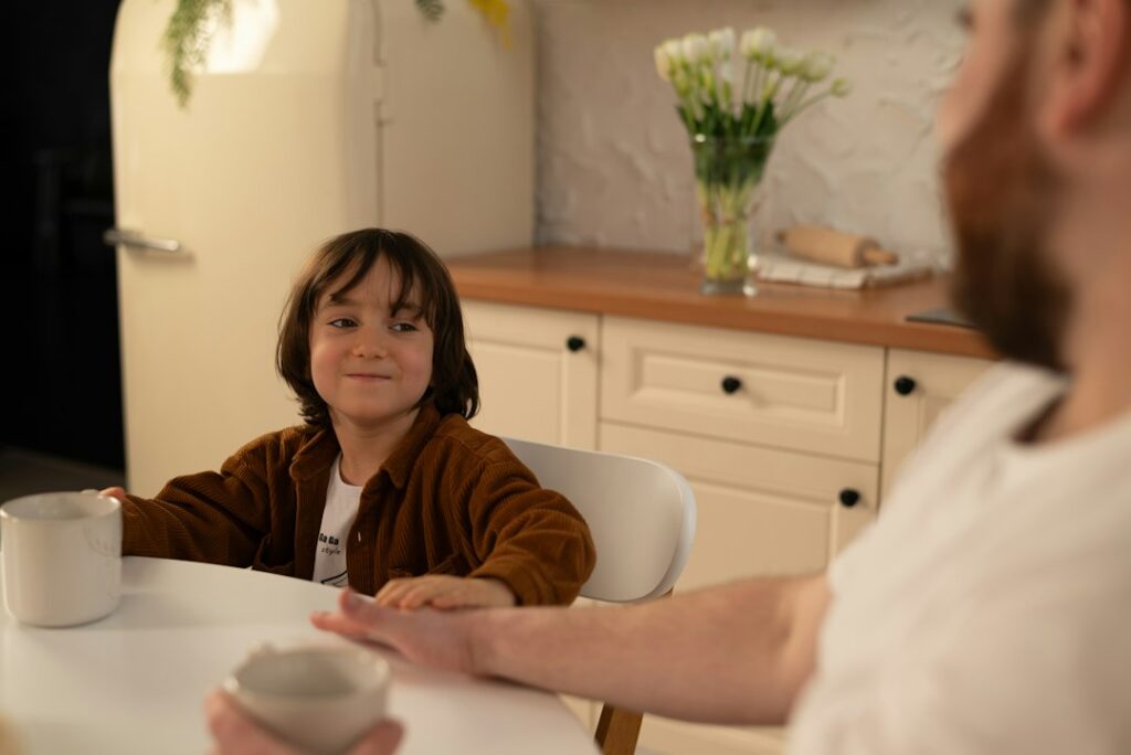 An adult and child talking together at a table, representing empathy, emotional awareness and thoughtful conversation