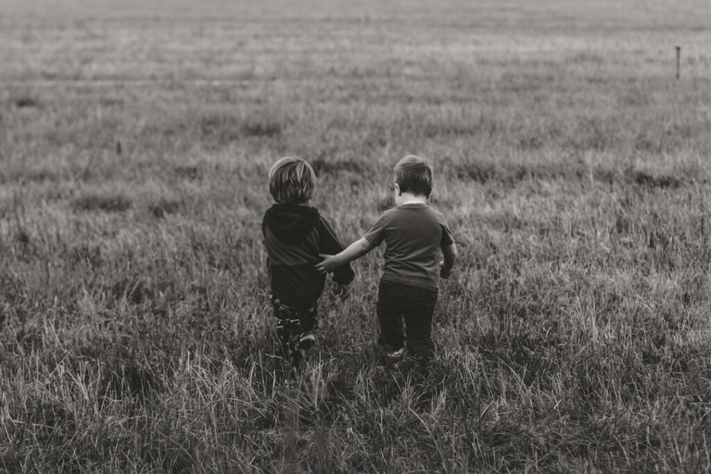 Two boys stepping beyond a boundary outdoors, symbolising choices, consequences and character development